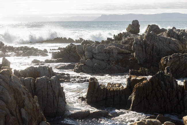 Зазубренные скалы на берегу в Де Келдерс, высокие волны катятся и разбиваются о скалы — стоковое фото