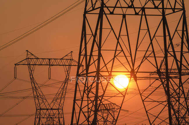 Електричний пілон та лінії електропередач з сонцем позаду . — стокове фото