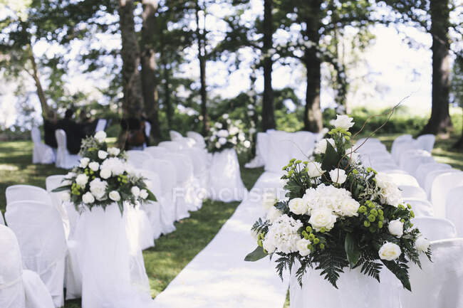 Сад со столами, накрытыми в тени высоких деревьев, накрытый на свадьбу — стоковое фото