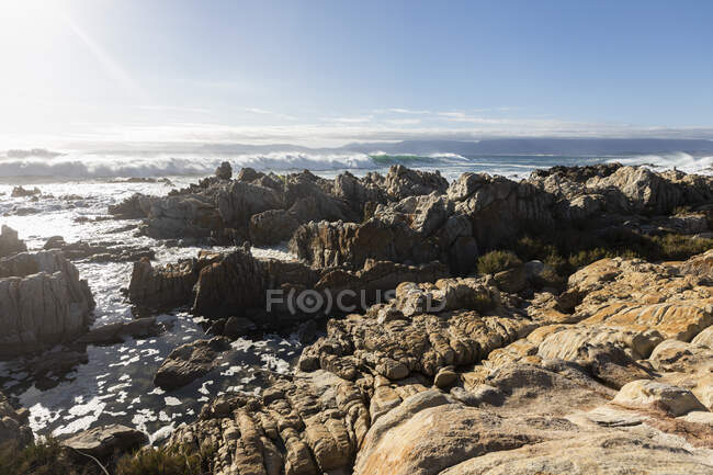 Rocas dentadas en la orilla de De Kelders, olas altas rodando y rompiendo sobre las rocas - foto de stock