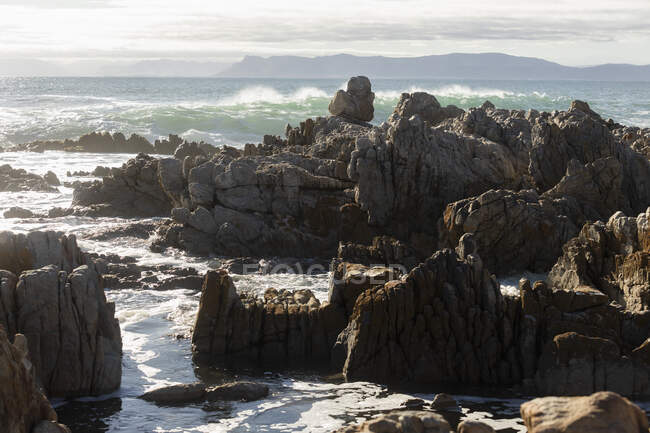 Rocce frastagliate sulla riva a De Kelders, onde alte che rotolano e si infrangono sulle rocce — Foto stock