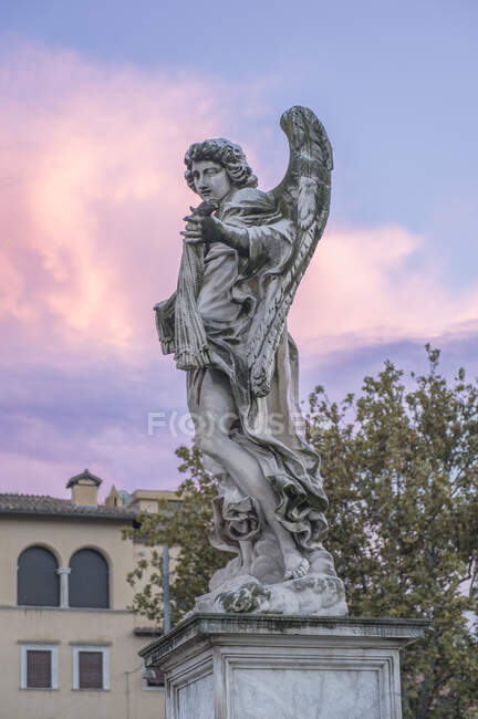 Estatua de un ángel con alas, cielo del amanecer - foto de stock