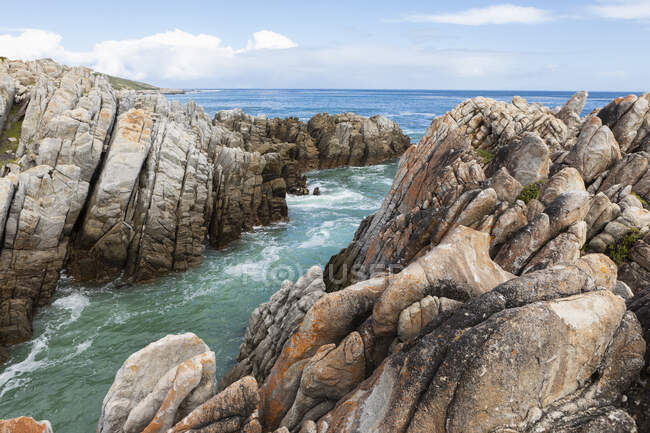 Rocas dentadas en la costa atlántica, olas en la superficie del agua. - foto de stock