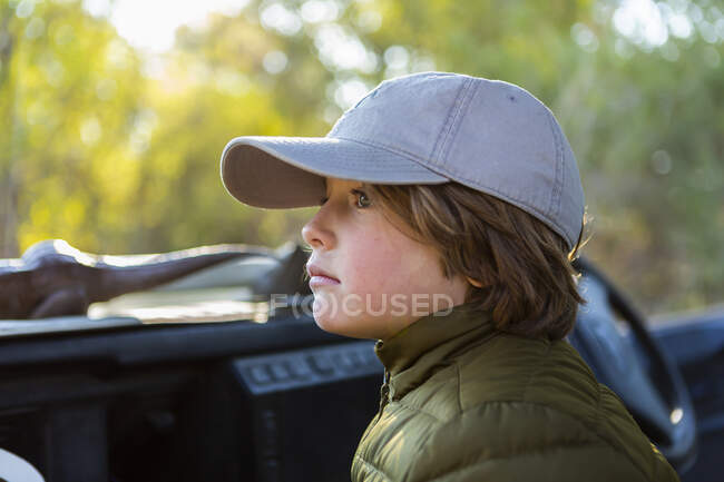 Ritratto di ragazzo con un berretto da baseball in un veicolo safari. — Foto stock