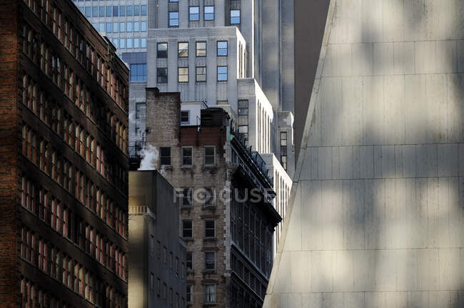 Edificios en la ciudad de Nueva York, vista desde abajo, arquitectura histórica y moderna, sombras y luz solar - foto de stock