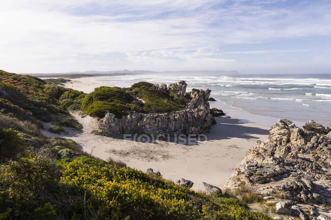 Песчаный пляж и скалы, возвышенный вид, волны, разбивающиеся о берег. — стоковое фото