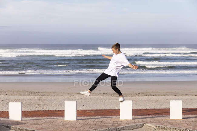 Дівчинка - підліток балансує на постах на піщаному пляжі.. — стокове фото