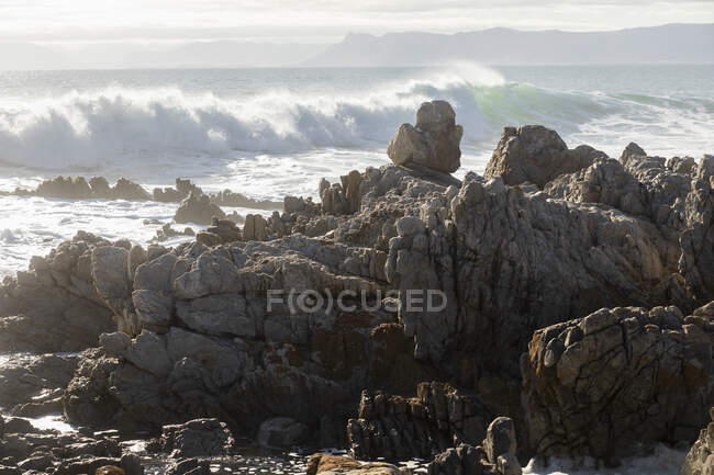 Rochers déchiquetés sur le rivage à De Kelders, de hautes vagues se précipitent et se cassent sur les rochers — Photo de stock