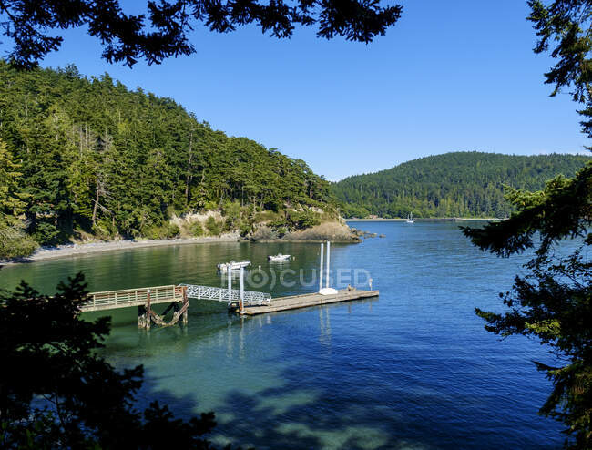 Dock in a bay surrounded by wooded hillsides. — Photo de stock