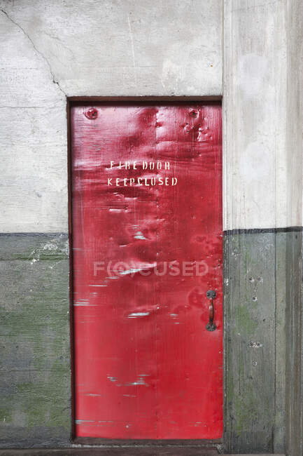 Una barriera rossa porta tagliafuoco in un museo, avviso Fire Door Keep Chiuso, ammaccature e segni sul metallo — Foto stock