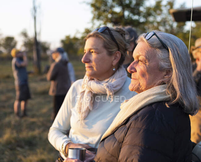 Zwei Menschen, eine reife Frau und ihre Mutter, stehen nebeneinander bei Sonnenuntergang — Stockfoto