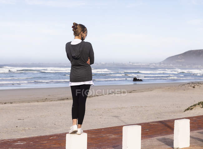Une adolescente équilibrant sur des poteaux sur une plage de sable. — Photo de stock