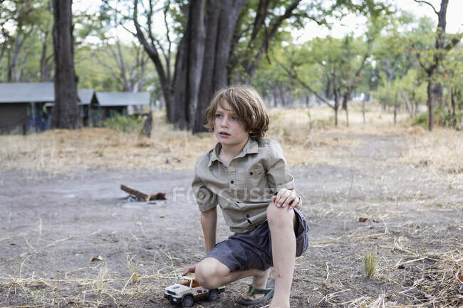 Мальчик в палаточном лагере на коленях на открытом пространстве, играет — стоковое фото