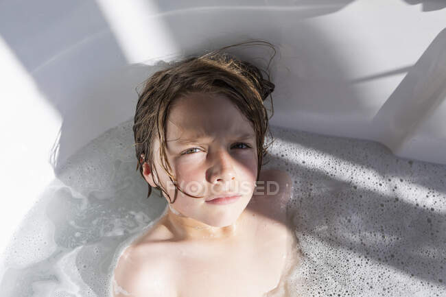 Garçon de huit ans dans une baignoire, prenant un bain — Photo de stock