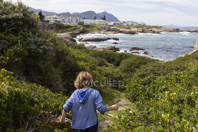 Young boy in a blue shirt walking on a path to the beach — Stock Photo