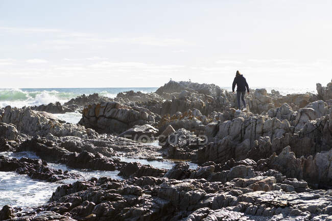 Adolescente chica escalando rocas, De Kelders, Sudáfrica - foto de stock