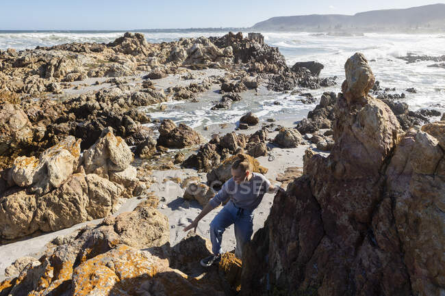 Dos niños explorando las rocas irregulares y la costa atlántica. - foto de stock