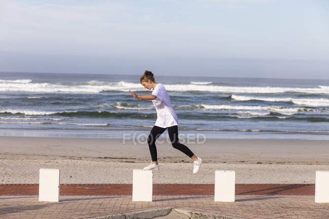 Une adolescente équilibrant sur des poteaux sur une plage de sable. — Photo de stock