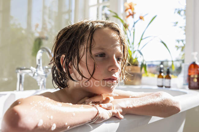 Garçon de huit ans dans une baignoire, prenant un bain — Photo de stock