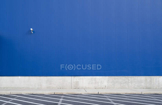 Caméra de surveillance sur un mur extérieur bleu d'entrepôt ou grand bâtiment sans fenêtre. — Photo de stock