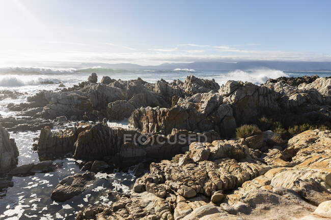Zerklüftete Felsen am Ufer bei De Kelders, hohe Wellen rollen herein und brechen an den Felsen — Stockfoto