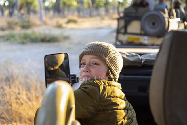 Un chico sentado en un jeep en un safari al amanecer - foto de stock