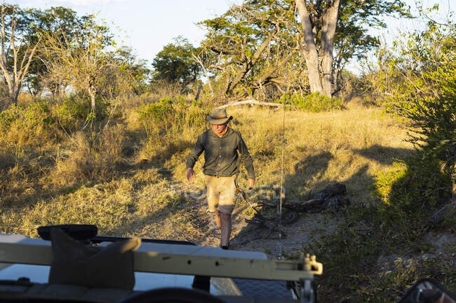 A safari guide looking at animal tracks on the ground. — Stock Photo