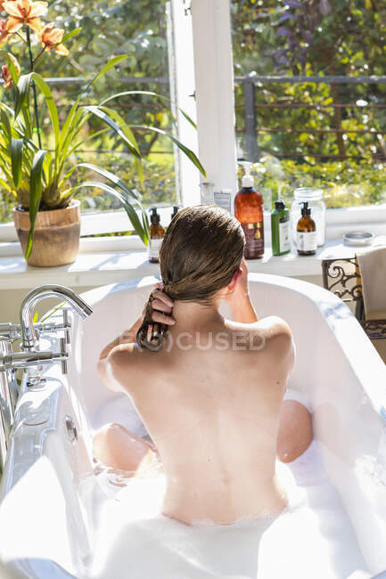 Ein Teenager wäscht sich in einer Badewanne die Haare — Stockfoto