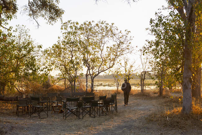 A man walking on a path at a safari camp by a water pool — Stock Photo