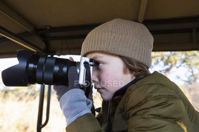 Niño de ocho años con una cámara en un jeep safari. - foto de stock