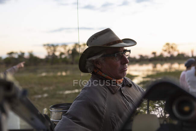 A safari guide seated in the driving seat of a jeep. — Stock Photo