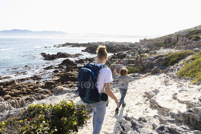 Дівчинка-підліток і молодший брат, що йде по прибережній стежці біля океану — стокове фото