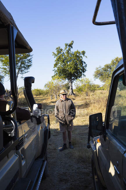 A safari guide by a jeep on a sunrise drive through a wildlife reserve. — Stock Photo