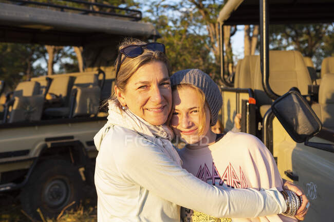 Una madre abrazando a su hija adolescente en unas vacaciones de safari familiar. - foto de stock