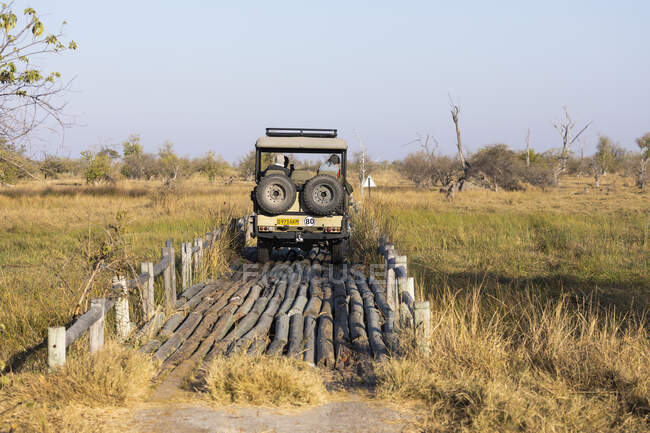 Ein Safari-Fahrzeug überquert eine Brücke in der Landschaft der Sümpfe und Wasserwege. — Stockfoto