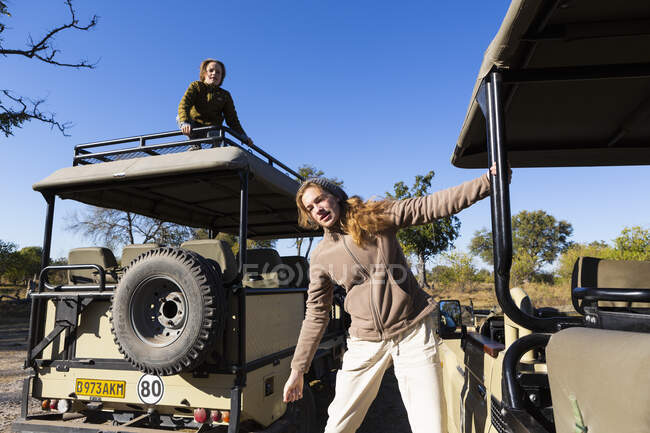 Teenage girl leaning out of a safari jeep, a boy on the roof of a vehicle — Stock Photo