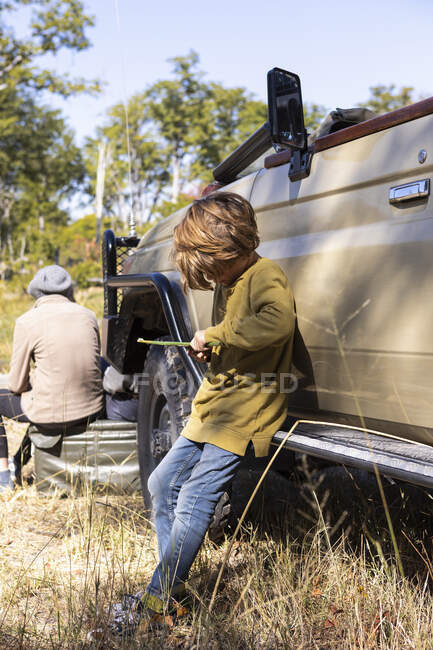 Un chico junto a un jeep de safari jugando con un juguete - foto de stock