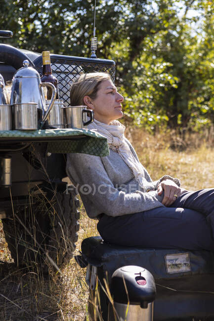 Erwachsene Frau sitzt in der Nähe von Safarifahrzeugen, Okavango Delta, Botswana — Stockfoto