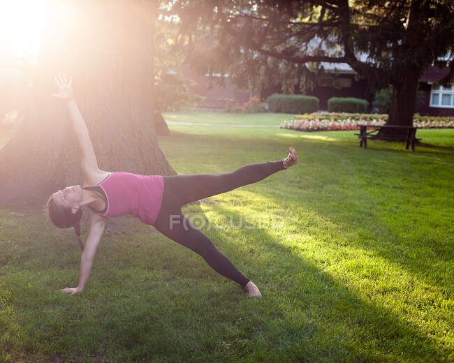 Woman balancing on side in yoga pose in park. — Stock Photo