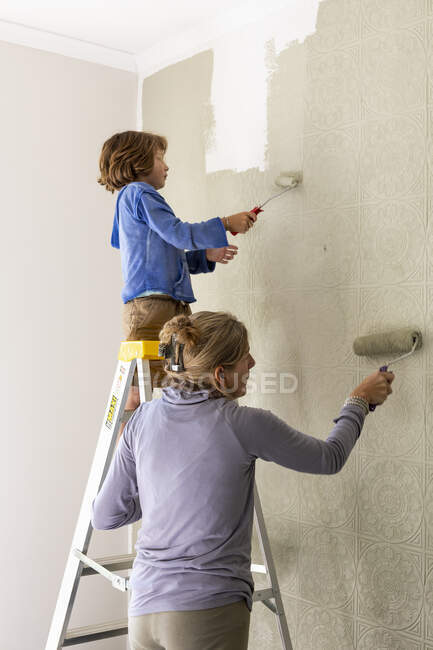 Une femme et un garçon de huit ans décorant une pièce, peignant des murs. — Photo de stock