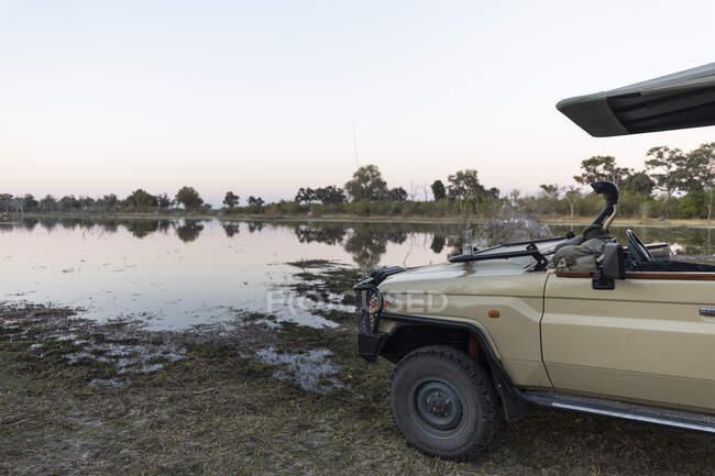 Um veículo de safári estacionado perto de uma via navegável no Delta do Okavango — Fotografia de Stock