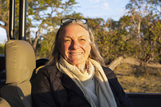 На заході сонця усміхається старша жінка, яка сидить у джипі.. — стокове фото