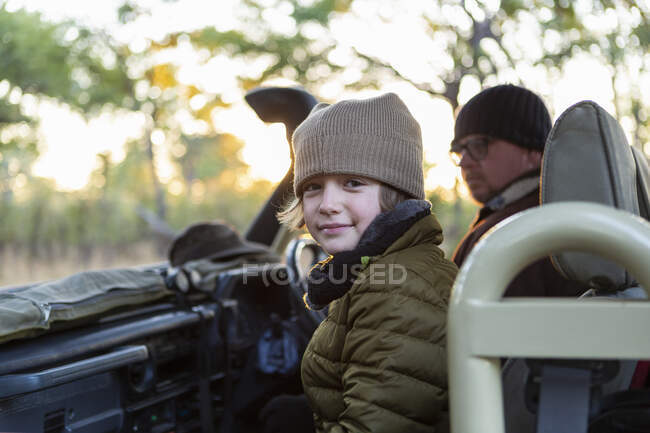 Хлопчик в капелюсі і пальто в джипі на сході сонця на сафарі . — стокове фото