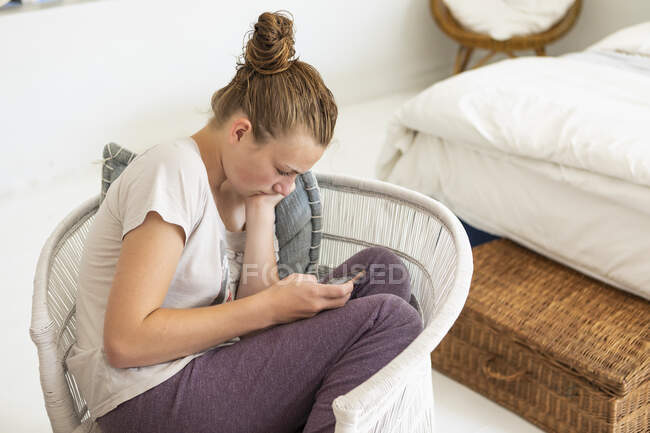 Teenage girl using smart phone in her bedroom — Stock Photo