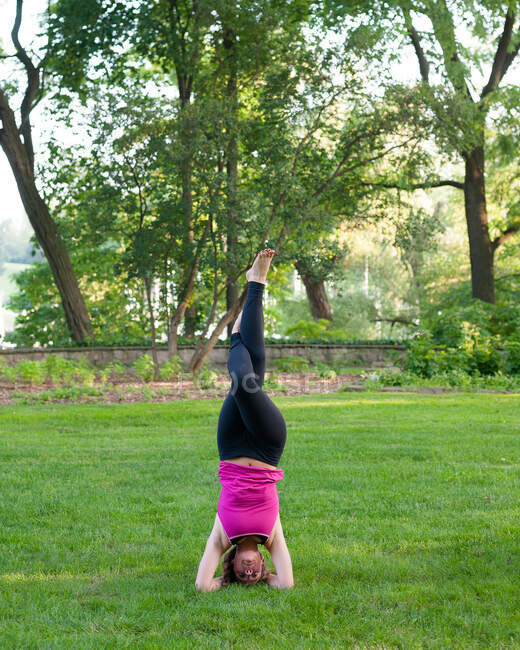 Mujer balanceándose en yoga posan en parque. - foto de stock