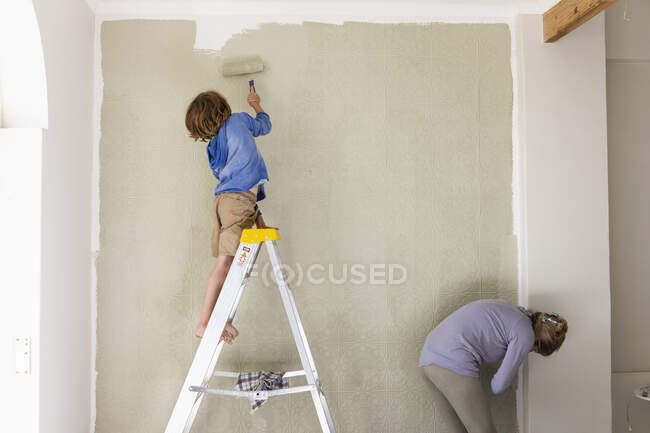 Женщина и восьмилетний мальчик украшают комнату, красят стены. — стоковое фото