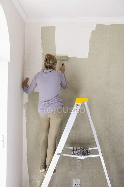 Une femme décorant une pièce, peignant des murs. — Photo de stock