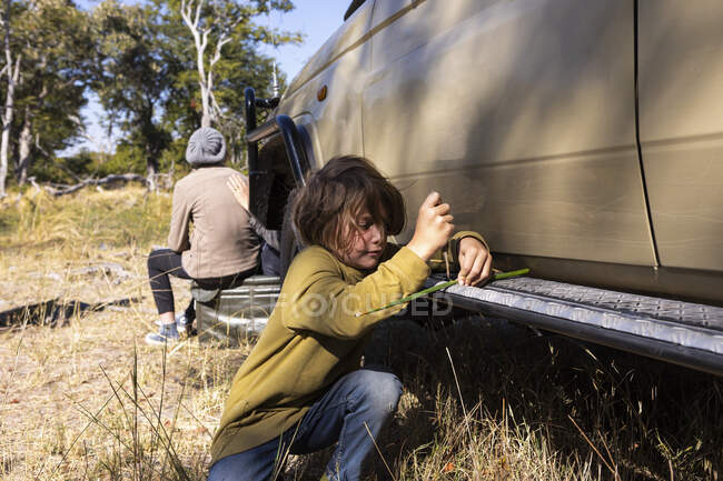 A boy by a safari jeep playing with a toy — Stock Photo