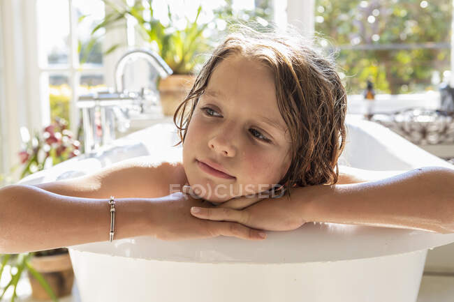 Garçon de huit ans dans la baignoire, tête et épaules. — Photo de stock