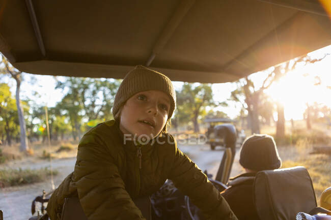 Мальчик, сидящий в джипе на сафари-драйве на рассвете — стоковое фото